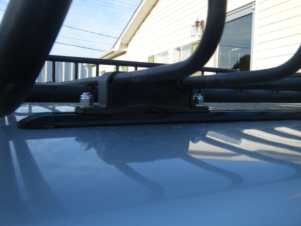 Close-up of a roof rack mounting bracket with bolts on a vehicle's roof
