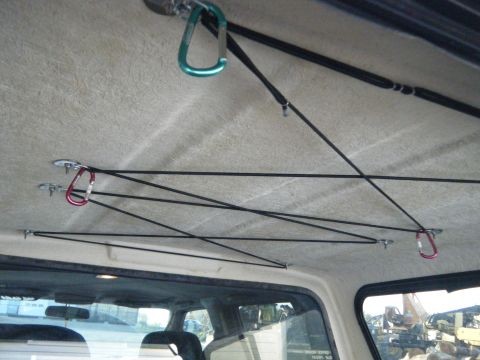 2003 Nissan Frontier - Bungee cords and carabiners are attached to the interior ceiling of a vehicle.