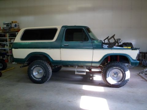 1979 Ford Bronco - Side view of a two-tone Ford Bronco undergoing work in a garage.