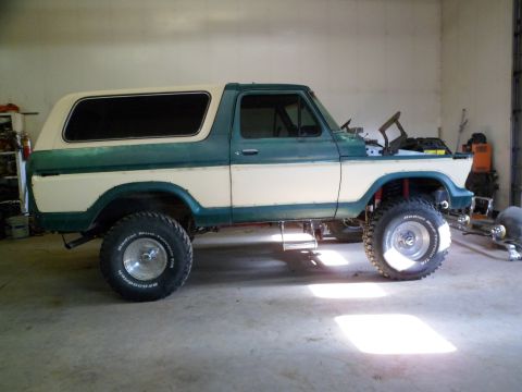 1979 Ford Bronco - This lifted Ford Bronco is in a garage, possibly undergoing maintenance or modification.