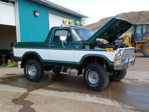 1979 Ford Bronco - This two-tone green and white 1979 Ford Bronco features an open hood, BFGoodrich tires, and decorative smiley face lights on the roof.