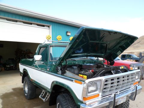 1979 Ford Bronco - Green and white 1979 Ford Bronco parked in front of a garage with hood up.