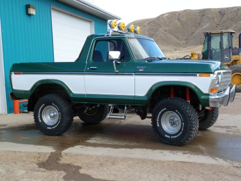 1979 Ford Bronco - This 1979 Ford Bronco features a two-tone green and white paint scheme, off-road tires, and auxiliary lighting on the roof.