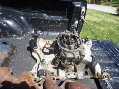 1979 Ford Bronco - Carburetor and intake manifold assembly resting in the bed of a pickup truck.