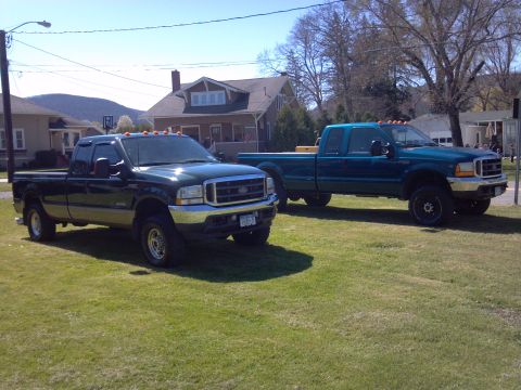 1993 Ford F-150 - Two Ford Super Duty pickup trucks are parked on a grassy area in front of houses.