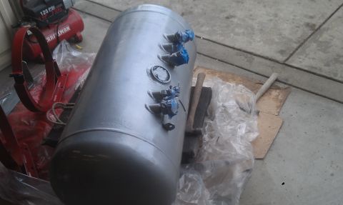 1978 Ford Bronco - A large propane tank sits on plastic sheeting next to a red air compressor and some tools.