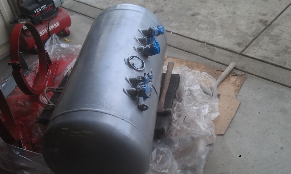 Propane tank with blue valves next to a red Craftsman air compressor