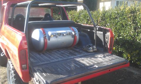1978 Ford Bronco - A red 1978 Ford Bronco is shown from the rear, with a large silver tank installed in its cargo bed.