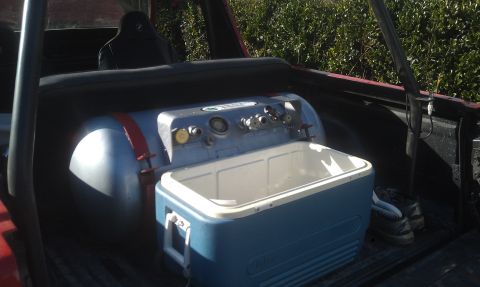 1978 Ford Bronco - Vehicle bed contains a propane tank and cooler, with a seat in the background.