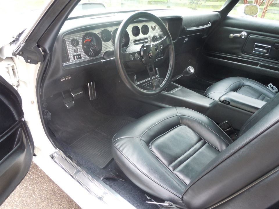 Interior view of a 1977 Pontiac Firebird Trans Am with black leather seats and dashboard
