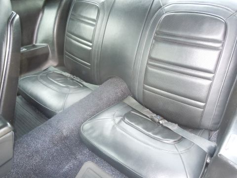 1973 Chevrolet Camaro - Interior view of black vinyl rear seats and carpet in a vintage car.