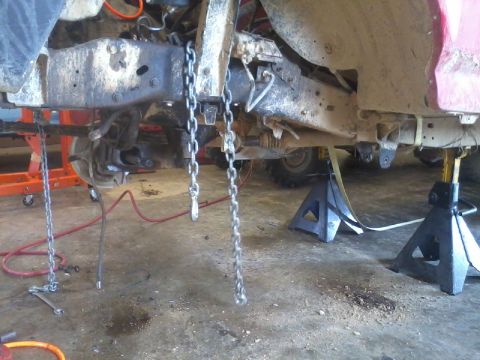 1995 Ford F-150 - The underside of a truck is shown with chains and jack stands, indicating repair or modification work.