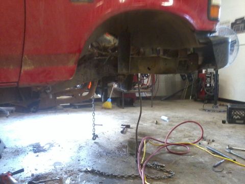 1995 Ford F-150 - Underbody of a 1995 Ford F-150 during a suspension modification, revealing the frame and drivetrain.