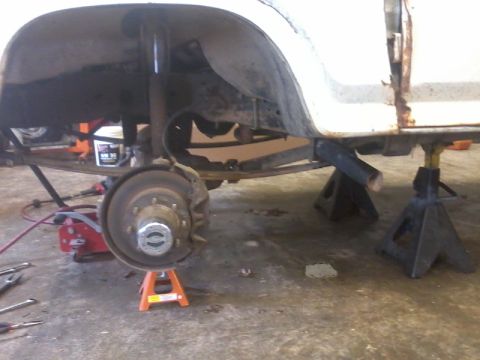 1995 Ford F-150 - The rear suspension and axle of a truck are supported by jack stands, with tools scattered around.