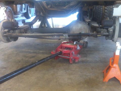 1995 Ford F-150 - The rear axle and suspension components of a truck are visible, supported by jack stands and a floor jack.