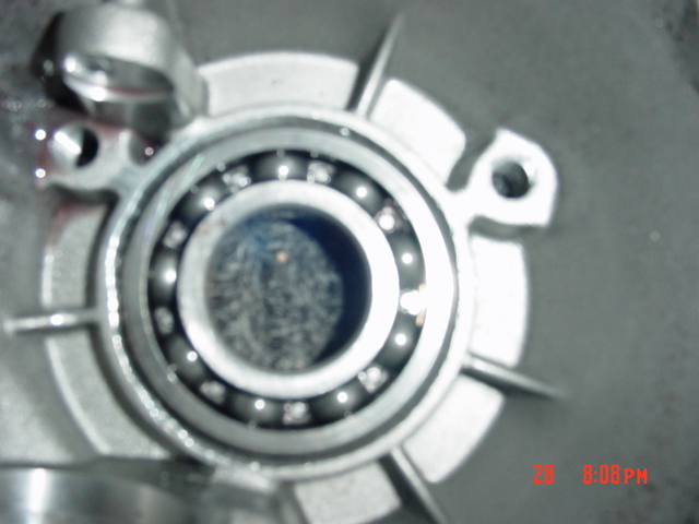 Close-up of a ball bearing pressed into an aluminum case with a worn or pitted center surface