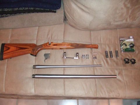 1996 Ford Bronco - Wooden rifle stock, two barrels, and various gun components are arranged on a tan surface.