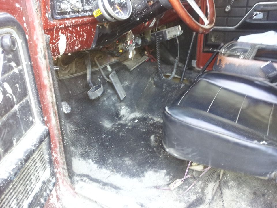 Interior view of a vehicle's driver side, showing floor, pedals, dashboard, and part of the steering wheel