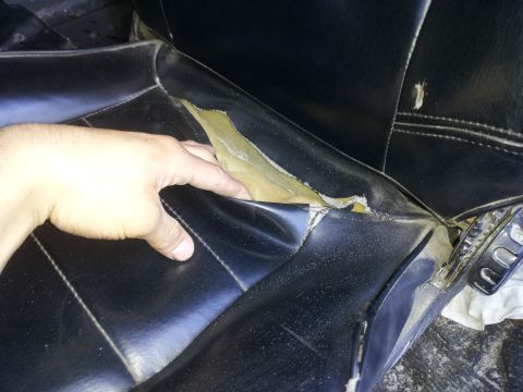 1978 Ford Bronco - Interior view of a damaged black vinyl seat with exposed foam, showing wear and tear.