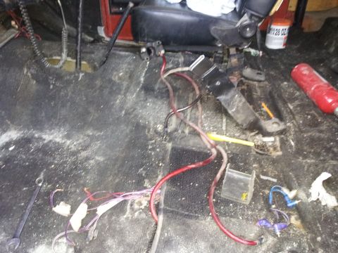 1978 Ford Bronco - The interior of a vehicle shows exposed wiring and a dirty floor, suggesting a work in progress or disrepair.