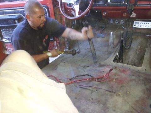 1978 Ford Bronco - A man is actively working on the interior of a vehicle, appearing to remove flooring or insulation.