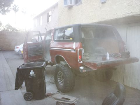 1978 Ford Bronco - Rear view of a red 1978 Ford Bronco with its doors and tailgate open, parked in a lot.