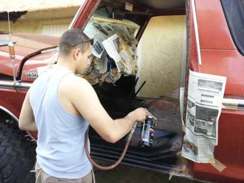 1978 Ford Bronco - Working on the interior of a 1978 Ford Bronco, masking off areas with newspaper before spraying.
