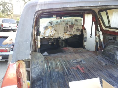 1978 Ford Bronco - The cargo area of a vehicle is visible, with newspaper taped to the rear window and signs of wear.