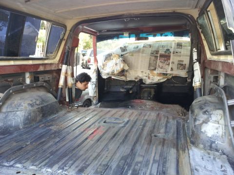 1978 Ford Bronco - The interior of a vehicle is shown, with the floor stripped bare and windows covered in newspaper, suggesting ongoing restoration work.