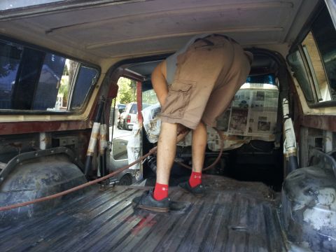 1978 Ford Bronco - A person is working on the interior of a vehicle, with another vehicle visible through the windows.