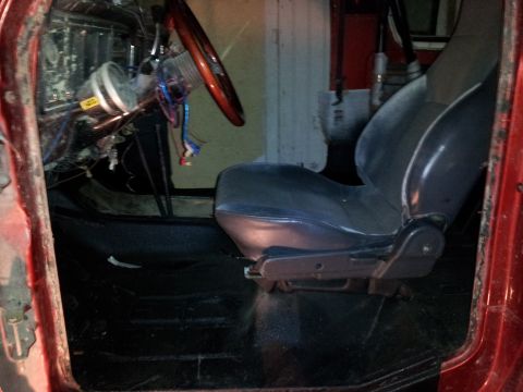 1978 Ford Bronco - The interior of a vehicle displays a driver's seat, steering wheel, and dashboard with visible wiring.