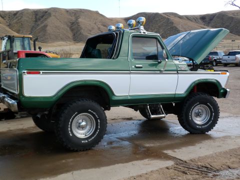 1979 Ford Bronco - A two-tone green and white Ford Bronco is parked outside with its hood up, showing off its engine bay.
