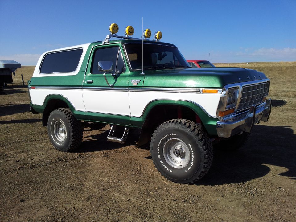 Green and white Ford Bronco with smiley face lights on roof, lifted suspension, and off-road tires