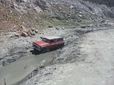 1978 Ford Bronco - A red 1978 Ford Bronco navigates a challenging muddy terrain.