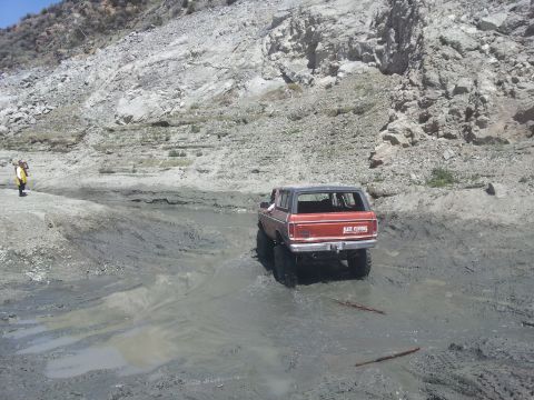 1978 Ford Bronco - A red 1978 Ford Bronco navigates a muddy trail in a rocky canyon.