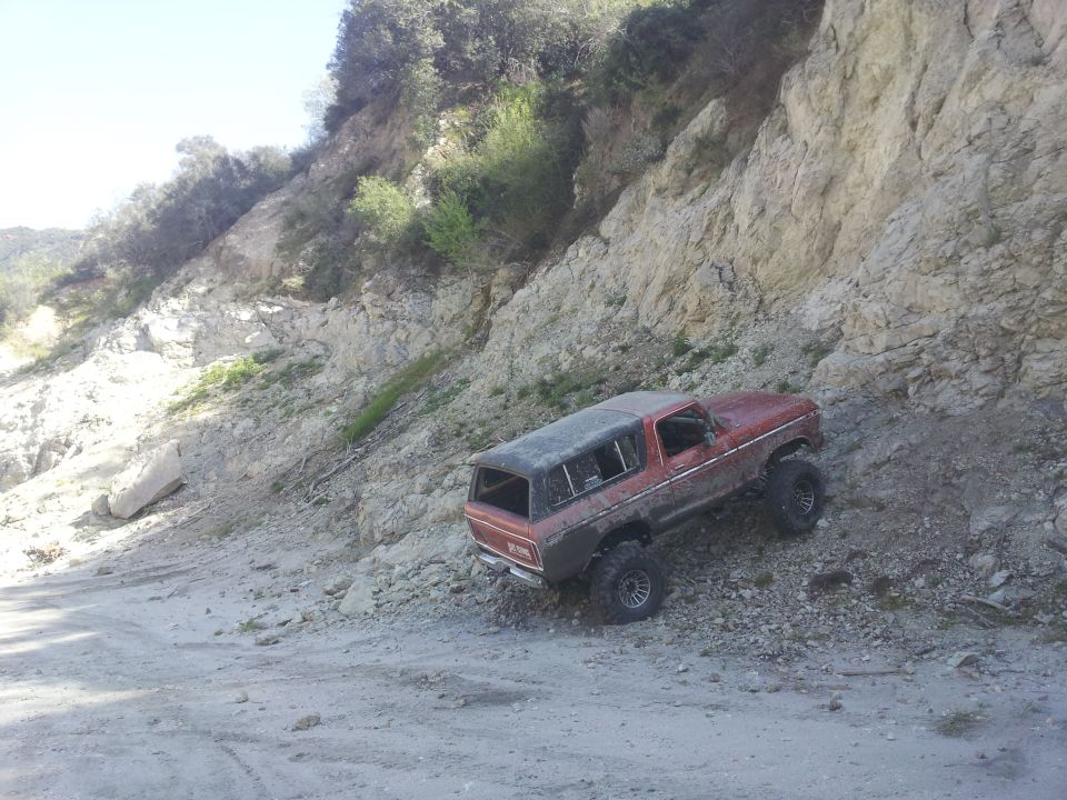Red 1978 Ford Bronco climbing a rocky hill