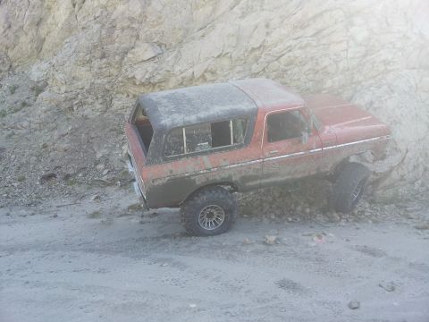 1978 Ford Bronco - This 1978 Ford Bronco is navigating a rough, off-road terrain with a rocky cliff face to its side.