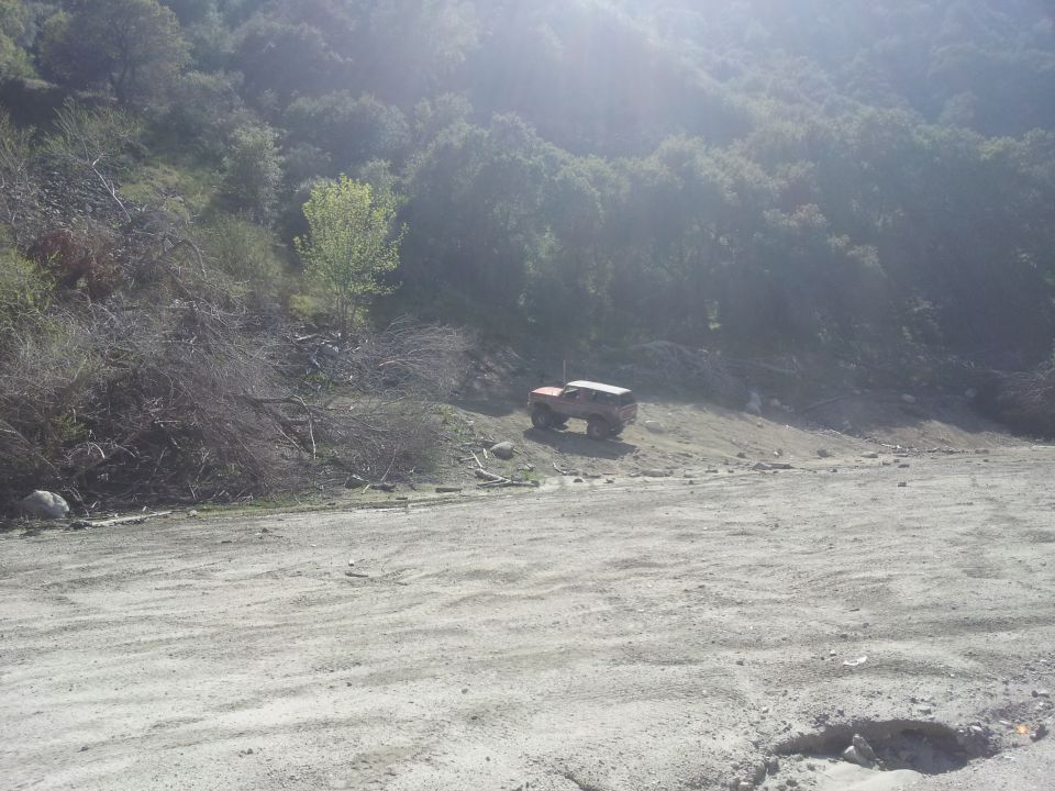 1978 Ford Bronco parked on a dirt slope with trees in the background