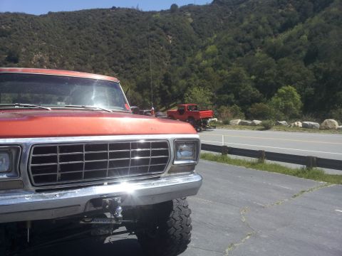 1978 Ford Bronco - Front view of an orange pickup truck, with a red pickup truck visible in the background.