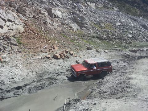 1978 Ford Bronco - This 1978 Ford Bronco navigates a challenging muddy path amidst a rocky, arid landscape.