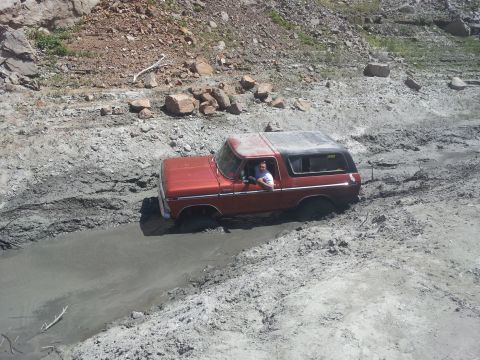 1978 Ford Bronco - A red 1978 Ford Bronco is shown struggling through a muddy off-road course.