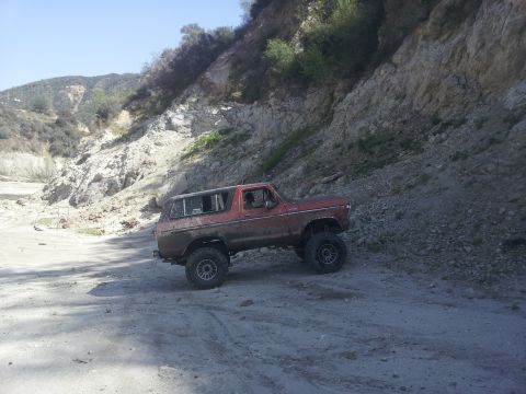 1978 Ford Bronco - This 1978 Ford Bronco is shown off-roading on a dirt path with a steep, rocky incline to its right.