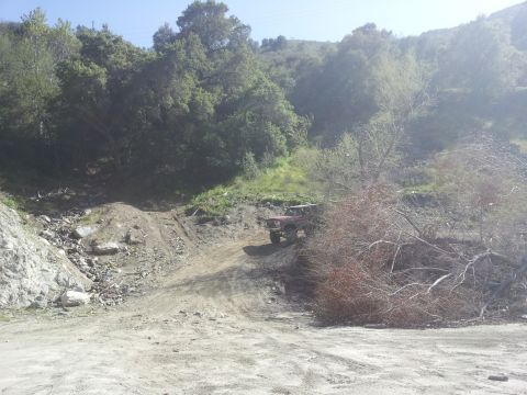 1978 Ford Bronco - A red off-road vehicle navigates a steep, rocky incline in a wooded area.