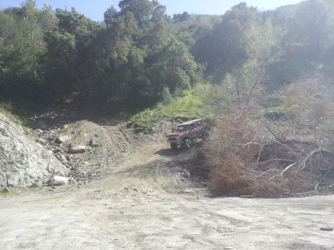 1978 Ford Bronco - A red 1978 Ford Bronco navigates a steep, dusty incline in a wooded area.