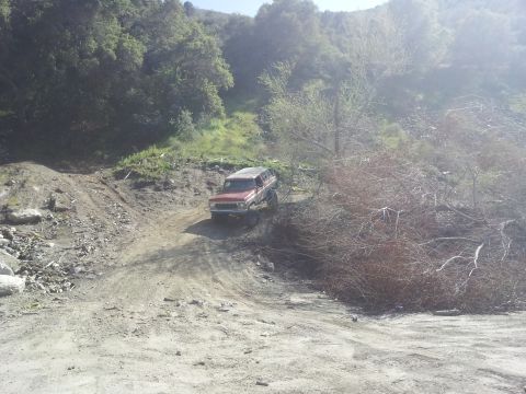 1978 Ford Bronco - 1978 Ford Bronco navigating a rough dirt trail in a wooded area.