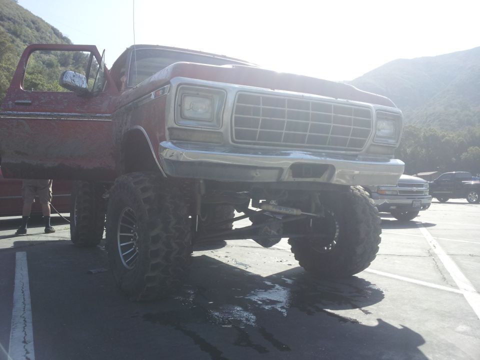 Red lifted 6x6 truck with large tires and a prominent grille