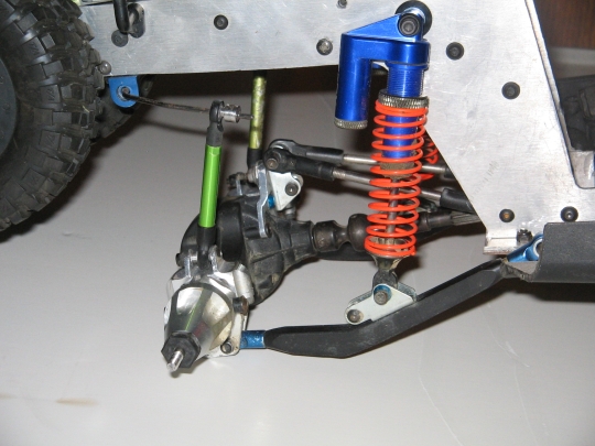 RC car suspension with blue shock and orange spring, metal chassis, and tire visible
