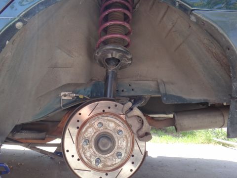 1995 Ford Taurus - Close-up of a rear wheel well showing a drilled brake rotor and a pink coilover suspension assembly.