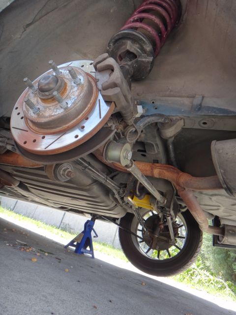 1995 Ford Taurus - The rear suspension and brake components of a vehicle are visible, supported by jack stands.