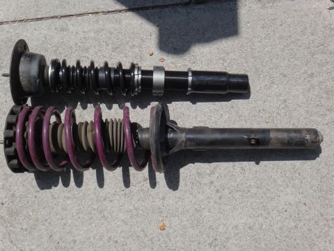 1995 Ford Taurus - Two automotive coilover suspension assemblies are displayed on a concrete surface, likely for sale or repair.